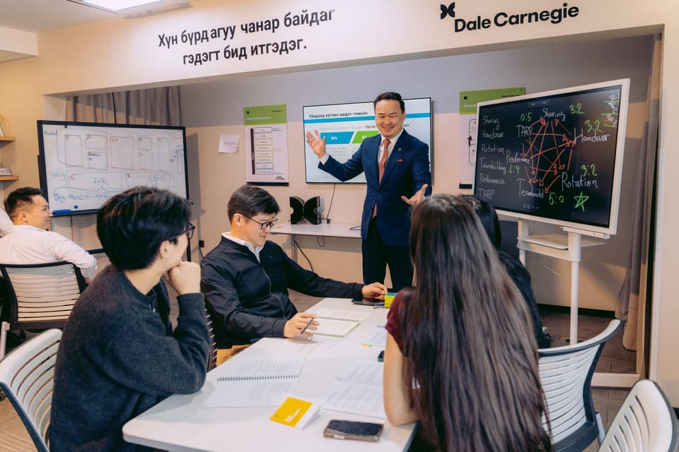 A trainer presenting beside the whiteboard in the training room